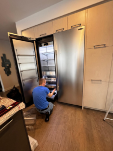 A technician puts a tray in a fridge during installation