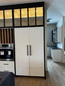 An integrated refrigerator installed in a cabinet with a cabinet door panel and a wall oven beside it